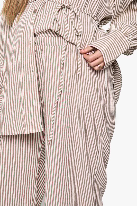 Wide leg maternity trousers with flattering silhouette for growing bumps
        Coordinating belt detail to adjust fit throughout pregnancy
        Vertical stripe pattern creates an elongating effect
        Comfortable high-rise waistband sits above the bump
        Designed to be paired with matching striped shirt for a coordinated look
    
    These boohoo maternity trousers combine comfort and style with their relaxed wide-leg design. The adjustable belt allows you to customise the fit as your body changes, while the vertical stripes create a lengthening effect for a flattering silhouette. Style with the matching button-up shirt for an on-trend coordinated set that works brilliantly for casual outings. For daytime gatherings, pair with simple trainers and oversized sunglasses, or dress up with ballet flats and delicate jewellery for family occasions. The versatile design transitions seamlessly between seasons-layer with a lightweight cardigan when temperatures drop or wear alone during warmer months. These trousers offer the perfect balance of comfort and contemporary style for the fashion-forward mum-to-be.
