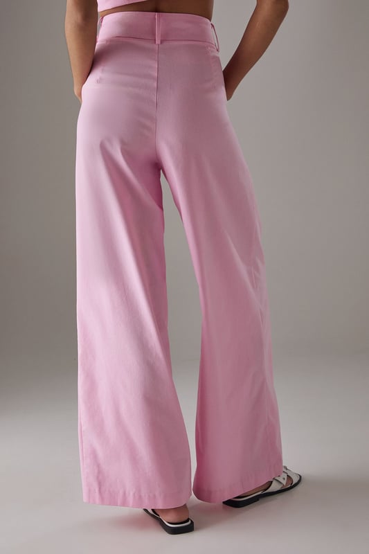 Tailored wide-leg silhouette with a dramatic flowing drape
        Elegant front pleats for added structure and dimension
        Distinctive side tie detail with decorative buttons for a feminine touch
        High-rise waistband designed to flatter the natural waistline
        Linen blend fabric offering breathability and a natural textured finish
    
    These statement trousers from Warehouse combine sophistication with contemporary flair. The wide-leg design creates a striking silhouette that moves beautifully with every step, whilst the tailored pleats add structure and refinement. Style with a simple white tee and flat sandals for effortless daytime chic, or pair with the matching waistcoat for a coordinated ensemble that's perfect for summer gatherings. The versatile design transitions seamlessly from casual brunches to family celebrations - simply swap your trainers for leather slides and add delicate jewellery to enhance the look. The linen blend fabric ensures these trousers remain comfortable throughout the day, making them an essential addition to your warm-weather wardrobe.