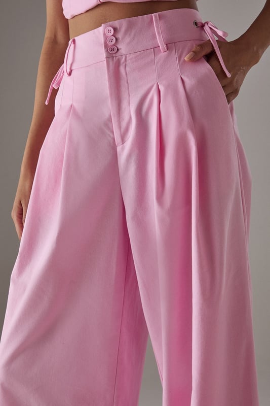Tailored wide-leg silhouette with a dramatic flowing drape
        Elegant front pleats for added structure and dimension
        Distinctive side tie detail with decorative buttons for a feminine touch
        High-rise waistband designed to flatter the natural waistline
        Linen blend fabric offering breathability and a natural textured finish
    
    These statement trousers from Warehouse combine sophistication with contemporary flair. The wide-leg design creates a striking silhouette that moves beautifully with every step, whilst the tailored pleats add structure and refinement. Style with a simple white tee and flat sandals for effortless daytime chic, or pair with the matching waistcoat for a coordinated ensemble that's perfect for summer gatherings. The versatile design transitions seamlessly from casual brunches to family celebrations - simply swap your trainers for leather slides and add delicate jewellery to enhance the look. The linen blend fabric ensures these trousers remain comfortable throughout the day, making them an essential addition to your warm-weather wardrobe.
