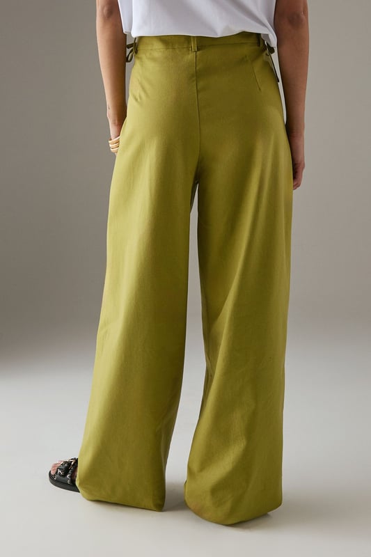 Tailored wide-leg silhouette with a dramatic flowing drape
        Elegant front pleats for added structure and dimension
        Distinctive side tie detail with decorative buttons for a feminine touch
        High-rise waistband designed to flatter the natural waistline
        Linen blend fabric offering breathability and a natural textured finish
    
    These statement trousers from Warehouse combine sophistication with contemporary flair. The wide-leg design creates a striking silhouette that moves beautifully with every step, whilst the tailored pleats add structure and refinement. Style with a simple white tee and flat sandals for effortless daytime chic, or pair with the matching waistcoat for a coordinated ensemble that's perfect for summer gatherings. The versatile design transitions seamlessly from casual brunches to family celebrations - simply swap your trainers for leather slides and add delicate jewellery to enhance the look. The linen blend fabric ensures these trousers remain comfortable throughout the day, making them an essential addition to your warm-weather wardrobe.