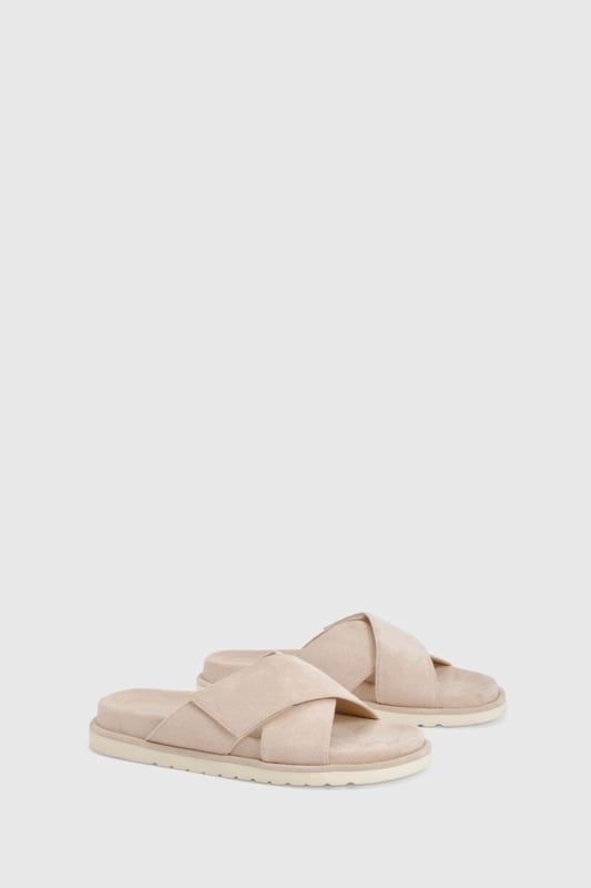 Distinctive cross strap design for a contemporary twist on classic footbed sliders
        Cushioned footbed providing all-day comfort for casual wear
        Flat heel measuring between 0-2cm, perfect for effortless walking
        Textured sole offering reliable grip on various surfaces
        Faux suede finish adding a touch of sophistication to a casual staple
    
    These cross strap footbed sliders combine style and practicality for your everyday wardrobe. The minimalist design features soft faux suede straps that gently hug your feet while the cushioned footbed ensures comfort with every step. Pair them with frayed hem denim shorts and an oversized linen shirt for a relaxed weekend brunch, or style with a flowing maxi dress for garden parties and seaside strolls. Their versatility extends to poolside lounging, where they make the perfect companion to your favourite swimwear. The neutral aesthetic allows these sliders to complement virtually any casual ensemble, making them an essential addition to your summer rotation. Their durable construction means they'll remain a faithful companion throughout the warmer months, ready to slip on whenever comfort calls.