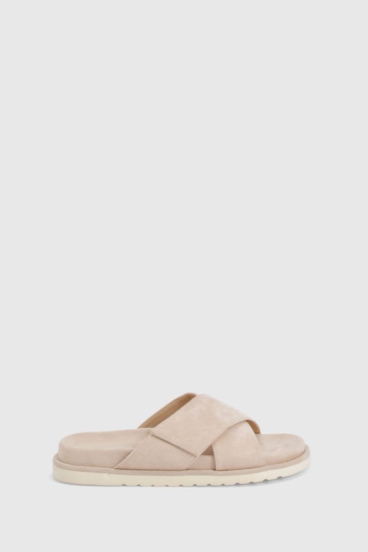 Distinctive cross strap design for a contemporary twist on classic footbed sliders
        Cushioned footbed providing all-day comfort for casual wear
        Flat heel measuring between 0-2cm, perfect for effortless walking
        Textured sole offering reliable grip on various surfaces
        Faux suede finish adding a touch of sophistication to a casual staple
    
    These cross strap footbed sliders combine style and practicality for your everyday wardrobe. The minimalist design features soft faux suede straps that gently hug your feet while the cushioned footbed ensures comfort with every step. Pair them with frayed hem denim shorts and an oversized linen shirt for a relaxed weekend brunch, or style with a flowing maxi dress for garden parties and seaside strolls. Their versatility extends to poolside lounging, where they make the perfect companion to your favourite swimwear. The neutral aesthetic allows these sliders to complement virtually any casual ensemble, making them an essential addition to your summer rotation. Their durable construction means they'll remain a faithful companion throughout the warmer months, ready to slip on whenever comfort calls.