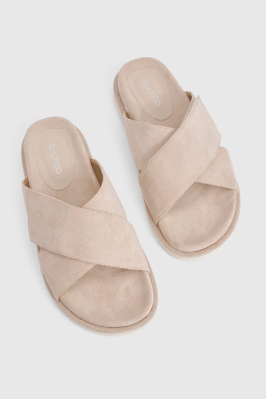 Distinctive cross strap design for a contemporary twist on classic footbed sliders
        Cushioned footbed providing all-day comfort for casual wear
        Flat heel measuring between 0-2cm, perfect for effortless walking
        Textured sole offering reliable grip on various surfaces
        Faux suede finish adding a touch of sophistication to a casual staple
    
    These cross strap footbed sliders combine style and practicality for your everyday wardrobe. The minimalist design features soft faux suede straps that gently hug your feet while the cushioned footbed ensures comfort with every step. Pair them with frayed hem denim shorts and an oversized linen shirt for a relaxed weekend brunch, or style with a flowing maxi dress for garden parties and seaside strolls. Their versatility extends to poolside lounging, where they make the perfect companion to your favourite swimwear. The neutral aesthetic allows these sliders to complement virtually any casual ensemble, making them an essential addition to your summer rotation. Their durable construction means they'll remain a faithful companion throughout the warmer months, ready to slip on whenever comfort calls.