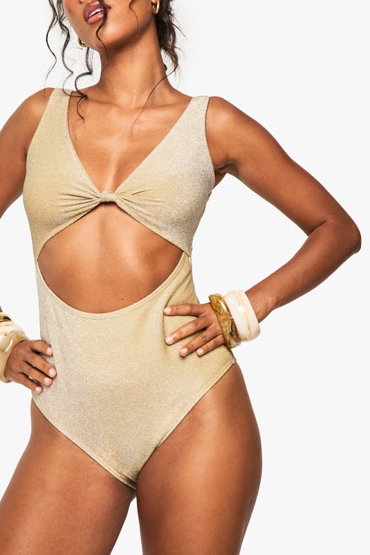 Striking cut-out design with a twist front detail for a fashion-forward beach look
        Glittering fabric catches the light beautifully as you move
        Flattering scoop back that complements the front cut-out
        Wide shoulder straps provide comfortable support for all-day wear
        Moderate coverage bottom with a high-cut leg to elongate your silhouette
    
    Make a dazzling statement poolside in this eye-catching Glitzer Cut-Out Swimsuit from Boohoo. The contemporary design features a striking twist-front detail and strategic cut-out that creates a captivating silhouette whilst maintaining the practicality of a one-piece. Perfect for those who want to stand out at beach clubs or resort holidays, this swimsuit can be styled with oversized sunglasses and wooden bangles for a complete look. The glittering fabric adds a touch of glamour to your beachwear collection, making it ideal for sunset cocktails by the pool or daytime lounging. Pair with a flowing kimono and metallic sandals when transitioning from beach to bar, or layer under denim shorts for casual beachside strolls. This versatile piece works brilliantly for both swimming and socialising, ensuring you remain the centre of attention wherever your summer adventures take you.