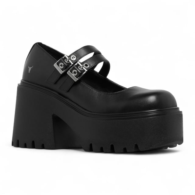Step into bold style with the Windsor Smith Lessons platform shoes — a modern twist on the classic Mary-Jane. Crafted with a smooth black leather upper, these chunky platforms feature twin adjustable straps with silver hardware, eyelet detailing, and Windsor Smith’s signature bull symbol on the side. Designed for statement-makers, they boast a cleated, lightweight PU sole, a towering 9 cm heel, and a 4.6 cm platform for comfort and impact. With a rounded toe and edgy detailing, they're perfect for elevating any outfit.

Upper: Premium Leather
Lining: Non-Leather
Sole: Lightweight PU
Closure: Twin adjustable straps with silver eyelets
Toe: Rounded
Platform Height: 4.6 cm
Heel Height: 9 cm
Details: Cleated sole, silver hardware, bull logo
