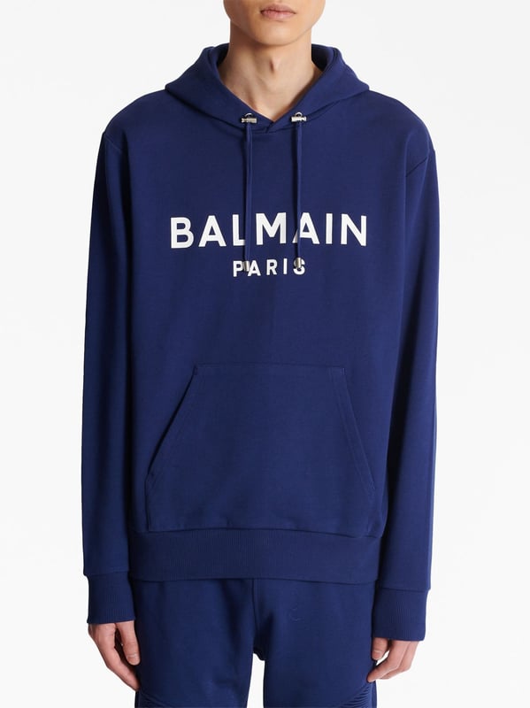 Balmain's Paris hoodie is a stylish hooded sweatshirt with a straight cut design. It features ribbed detailing and an adjustable drawstring neckline for a comfortable fit. The long sleeves and kangaroo pocket add a practical touch, while the chest logo adds a subtle branding element. Perfect for casual, everyday wear.