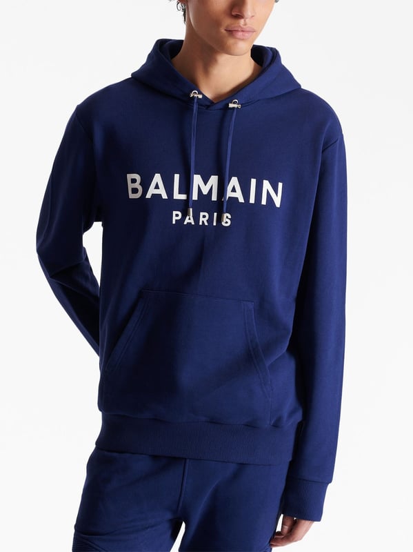 Balmain's Paris hoodie is a stylish hooded sweatshirt with a straight cut design. It features ribbed detailing and an adjustable drawstring neckline for a comfortable fit. The long sleeves and kangaroo pocket add a practical touch, while the chest logo adds a subtle branding element. Perfect for casual, everyday wear.