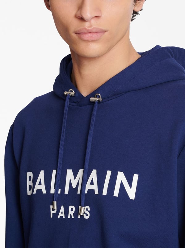 Balmain's Paris hoodie is a stylish hooded sweatshirt with a straight cut design. It features ribbed detailing and an adjustable drawstring neckline for a comfortable fit. The long sleeves and kangaroo pocket add a practical touch, while the chest logo adds a subtle branding element. Perfect for casual, everyday wear.