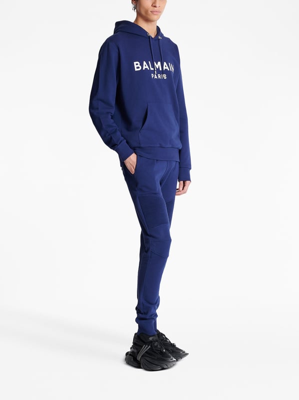 Balmain's Paris hoodie is a stylish hooded sweatshirt with a straight cut design. It features ribbed detailing and an adjustable drawstring neckline for a comfortable fit. The long sleeves and kangaroo pocket add a practical touch, while the chest logo adds a subtle branding element. Perfect for casual, everyday wear.