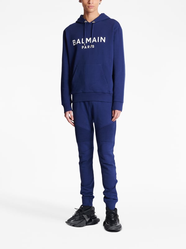 Balmain's Paris hoodie is a stylish hooded sweatshirt with a straight cut design. It features ribbed detailing and an adjustable drawstring neckline for a comfortable fit. The long sleeves and kangaroo pocket add a practical touch, while the chest logo adds a subtle branding element. Perfect for casual, everyday wear.