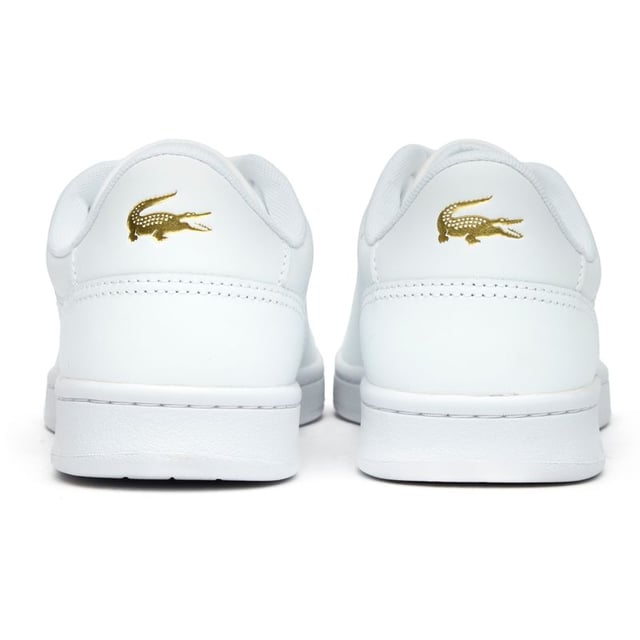 The Lacoste Carnaby Set brings classic court style to your casual collection. These elegant white leather trainers showcase subtle metallic accents that catch the light as you move. With Lacoste's signature branding tastefully placed on the tongue, heel, and quarter, these shoes offer understated luxury. The sturdy rubber cup sole provides reliable traction and durability for everyday wear. Perfect for pairing with anything from tailored trousers to summer dresses.