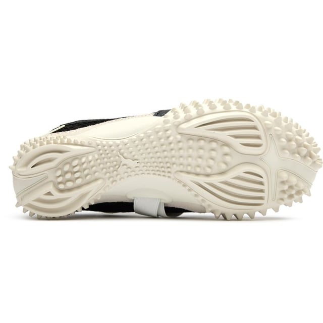 Der Puma Mostro in elegantem Schwarz verwandelt lässiges Schuhwerk mit seinem grenzüberschreitenden Design. Diese hybride Kreation vereint Komfort und unkonventionelle Ästhetik und präsentiert ein markantes, skulpturales Profil, das Aufmerksamkeit erregt. Das strapazierfähige Obermaterial aus Nylon ruht auf einer avantgardistischen Gummisohle mit Spitzen, die unerwarteten Halt bietet, während sie eine schlanke, flache Silhouette beibehält. Perfekt für Trendsetter, die Pumas Erbe innovativer Sportbekleidung mit einem mutigen, zeitgenössischen Twist schätzen.