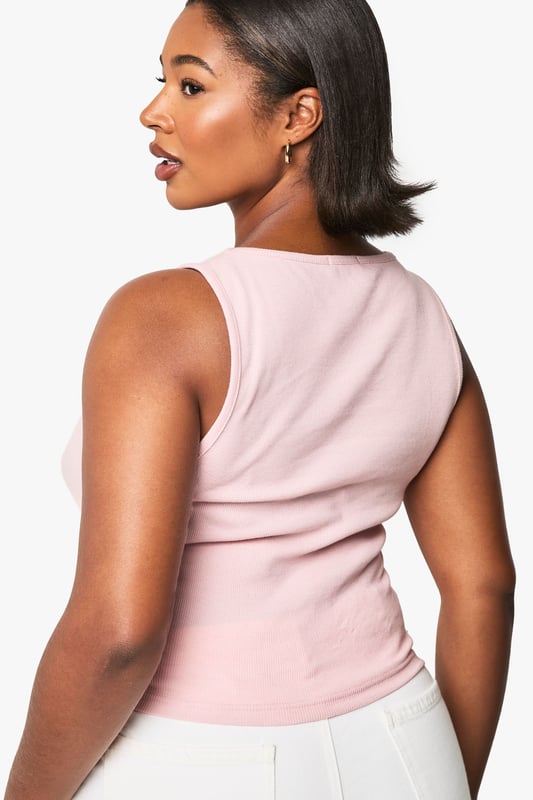 Flattering scoop neckline that frames the dcolletage beautifully
        Sleek racer back design for enhanced freedom of movement
        Ribbed fabric that offers a comfortable, body-hugging fit
        Versatile cropped length perfect for layering or wearing alone
        Plus size design crafted specifically to complement fuller figures
    
    This essential ribbed vest top combines comfort with contemporary style for your everyday wardrobe. The scoop neckline adds a feminine touch while the racer back design creates a sporty silhouette that works brilliantly for casual outfits. As seen on our model, layer it under an oversized shirt with wide-leg trousers for an effortlessly chic daytime look, or pair with high-waisted jeans and trainers for running weekend errands. The form-fitting ribbed texture offers just the right amount of stretch to move with you throughout the day, making this Boohoo top a versatile staple for athleisure styling. Perfect for transitional weather when worn under a light jacket, or as a standalone piece during warmer months. This vest top effortlessly bridges the gap between comfort and urban style.