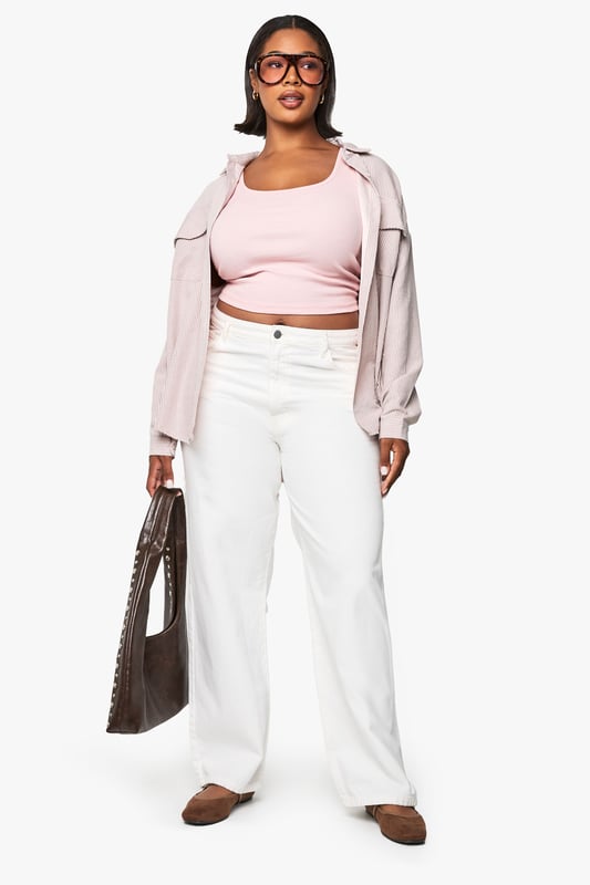Flattering scoop neckline that frames the dcolletage beautifully
        Sleek racer back design for enhanced freedom of movement
        Ribbed fabric that offers a comfortable, body-hugging fit
        Versatile cropped length perfect for layering or wearing alone
        Plus size design crafted specifically to complement fuller figures
    
    This essential ribbed vest top combines comfort with contemporary style for your everyday wardrobe. The scoop neckline adds a feminine touch while the racer back design creates a sporty silhouette that works brilliantly for casual outfits. As seen on our model, layer it under an oversized shirt with wide-leg trousers for an effortlessly chic daytime look, or pair with high-waisted jeans and trainers for running weekend errands. The form-fitting ribbed texture offers just the right amount of stretch to move with you throughout the day, making this Boohoo top a versatile staple for athleisure styling. Perfect for transitional weather when worn under a light jacket, or as a standalone piece during warmer months. This vest top effortlessly bridges the gap between comfort and urban style.