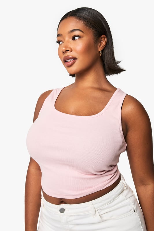 Flattering scoop neckline that frames the dcolletage beautifully
        Sleek racer back design for enhanced freedom of movement
        Ribbed fabric that offers a comfortable, body-hugging fit
        Versatile cropped length perfect for layering or wearing alone
        Plus size design crafted specifically to complement fuller figures
    
    This essential ribbed vest top combines comfort with contemporary style for your everyday wardrobe. The scoop neckline adds a feminine touch while the racer back design creates a sporty silhouette that works brilliantly for casual outfits. As seen on our model, layer it under an oversized shirt with wide-leg trousers for an effortlessly chic daytime look, or pair with high-waisted jeans and trainers for running weekend errands. The form-fitting ribbed texture offers just the right amount of stretch to move with you throughout the day, making this Boohoo top a versatile staple for athleisure styling. Perfect for transitional weather when worn under a light jacket, or as a standalone piece during warmer months. This vest top effortlessly bridges the gap between comfort and urban style.