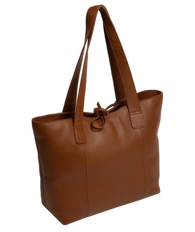 Handcrafted from natural leather with a soft to the touch pebble grain finish, the 'Carolina' tote bag from NiNa Amora is a must-have accessory. A unique tie top secures the central lined compartment which includes a zipped compartment which divides the design; perfect for maintaining an organised bag. Additional storage space is provided by a slip and zipped pocket on the interior, ideal for your phone, keys and any other essentials while out and about. Adorned with dual leather handles with a drop length of 25cm for a comfortable and versatile carrying options. Silver metal fittings and zips give this design a elegant look which is complemented the NiNa Amora X logo is silver foil embossed on the front and hanging charm for a luxurious finishing touch.