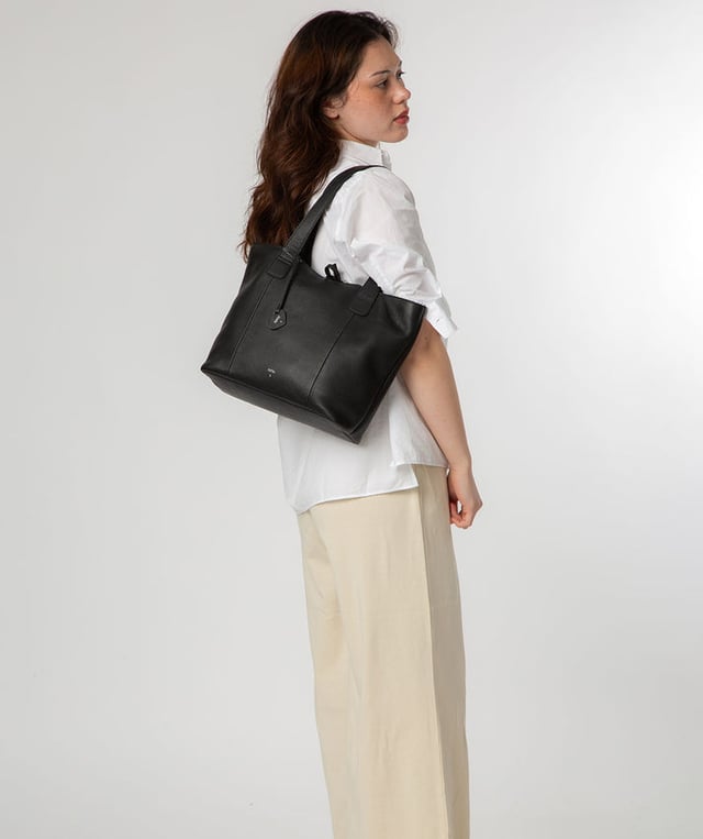 Handcrafted from natural leather with a soft to the touch pebble grain finish, the 'Carolina' tote bag from NiNa Amora is a must-have accessory. A unique tie top secures the central lined compartment which includes a zipped compartment which divides the design; perfect for maintaining an organised bag. Additional storage space is provided by a slip and zipped pocket on the interior, ideal for your phone, keys and any other essentials while out and about. Adorned with dual leather handles with a drop length of 25cm for a comfortable and versatile carrying options. Silver metal fittings and zips give this design a elegant look which is complemented the NiNa Amora X logo is silver foil embossed on the front and hanging charm for a luxurious finishing touch.