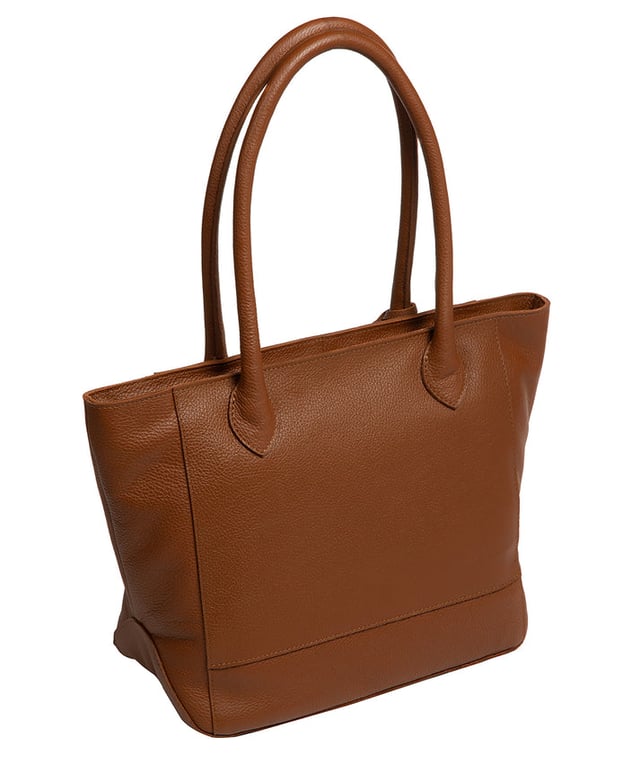As part of the NiNa Amora brand, the 'Margarida' tote bag is inspired by our designer's daughter and all about elevating classic designs with high quality leather. A concealed zip-over top secures the spacious main lined compartment which opens to reveal additional storage space in the form of a slip and zipped pocket; ideal for your phone, keys and any other essentials. The classic angular sides of the tote are updated with this sophisticated design and adorned with slim leather handles with a drop length of 20cm. This bag is finished with sophisticated silver metal fittings and zips which are complemented by the NiNa Amora X logo embossed in silver on the front and on the hanging charm. Effortlessly chic.