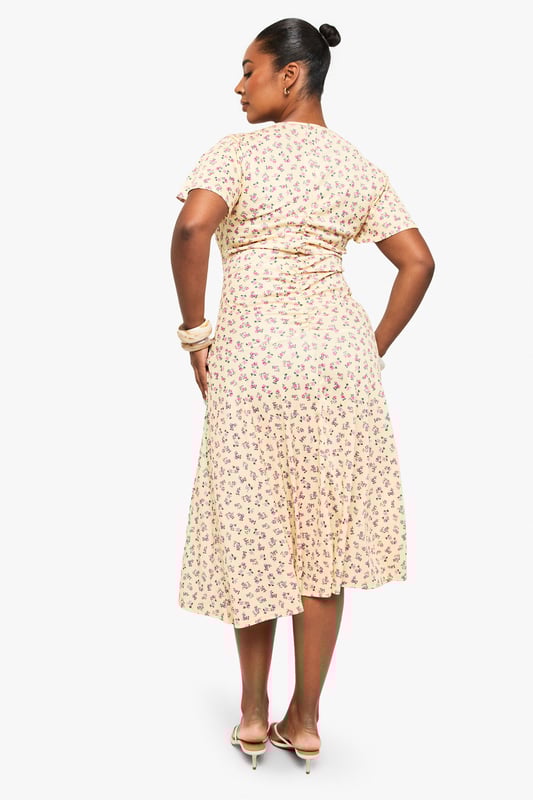 Flattering ruched detailing across the bodice for a figure-enhancing silhouette
        Feminine flutter sleeves adding movement and softness to the overall look
        Elegant V-neckline that frames the dcolletage beautifully
        Flowing midi-length skirt with gentle flare for ease of movement
        Versatile mesh fabric that drapes gracefully over curves
    
    This charming plus-size midi dress from Boohoo combines comfort with effortless style. The thoughtfully placed ruching creates a flattering shape while the delicate flutter sleeves add a touch of romance. Perfect for day-to-night versatility, pair with strappy sandals and a clutch as shown for daytime gatherings, or transform your look with statement jewellery and heeled boots for evening occasions. The flowing midi length offers both sophistication and practicality, making it ideal for office wear with a tailored blazer or weekend brunches with a denim jacket. The all-over pattern adds visual interest without overwhelming, whilst the V-neckline creates a balanced silhouette. This dress embodies Boohoo's commitment to inclusive fashion that transitions seamlessly between casual and more formal settings.