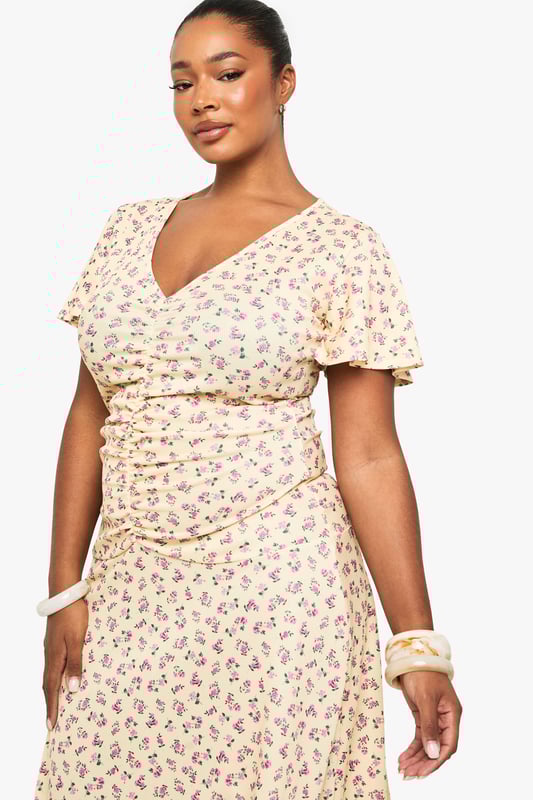 Flattering ruched detailing across the bodice for a figure-enhancing silhouette
        Feminine flutter sleeves adding movement and softness to the overall look
        Elegant V-neckline that frames the dcolletage beautifully
        Flowing midi-length skirt with gentle flare for ease of movement
        Versatile mesh fabric that drapes gracefully over curves
    
    This charming plus-size midi dress from Boohoo combines comfort with effortless style. The thoughtfully placed ruching creates a flattering shape while the delicate flutter sleeves add a touch of romance. Perfect for day-to-night versatility, pair with strappy sandals and a clutch as shown for daytime gatherings, or transform your look with statement jewellery and heeled boots for evening occasions. The flowing midi length offers both sophistication and practicality, making it ideal for office wear with a tailored blazer or weekend brunches with a denim jacket. The all-over pattern adds visual interest without overwhelming, whilst the V-neckline creates a balanced silhouette. This dress embodies Boohoo's commitment to inclusive fashion that transitions seamlessly between casual and more formal settings.