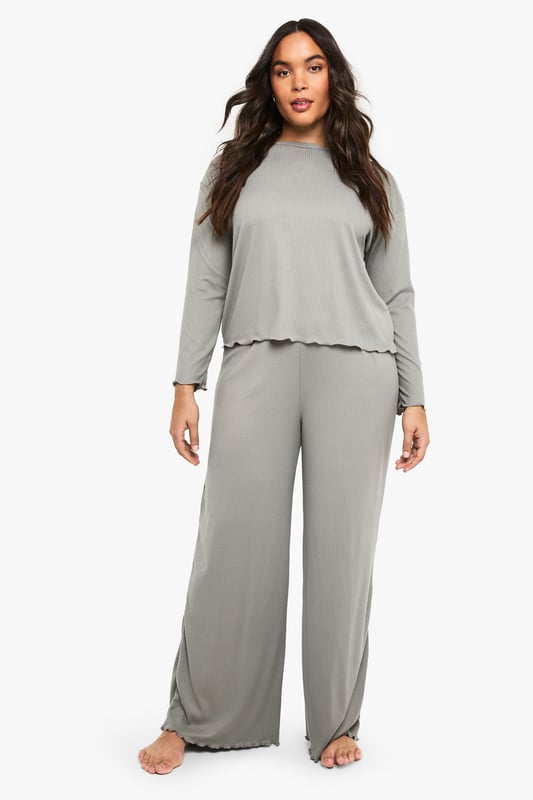 Ribbed texture throughout for added comfort and visual interest
        Relaxed long-sleeve top with distinctive ruffle-trimmed hem
        Wide-leg trousers with matching ruffle detail at the hem
        Soft, stretchy fabric ensures unrestricted movement
        Inclusive plus-size design that flatters your natural silhouette
    
    Embrace laid-back luxury with this Boohoo ribbed loungewear set, thoughtfully designed for those moments when comfort is non-negotiable but style remains essential. The top features a relaxed fit with a playful ruffled hem that adds a feminine touch to casual wear, while the coordinating wide-leg trousers create a balanced silhouette that moves beautifully with you. Perfect for weekend brunches at home, film nights with friends, or simply unwinding after a busy day. Layer with a chunky cardigan and fluffy slippers during colder months, or wear the top with your favourite denim for a quick dash to the shops. This versatile set transitions effortlessly between lounging and casual outings, making it an indispensable addition to your off-duty wardrobe.
