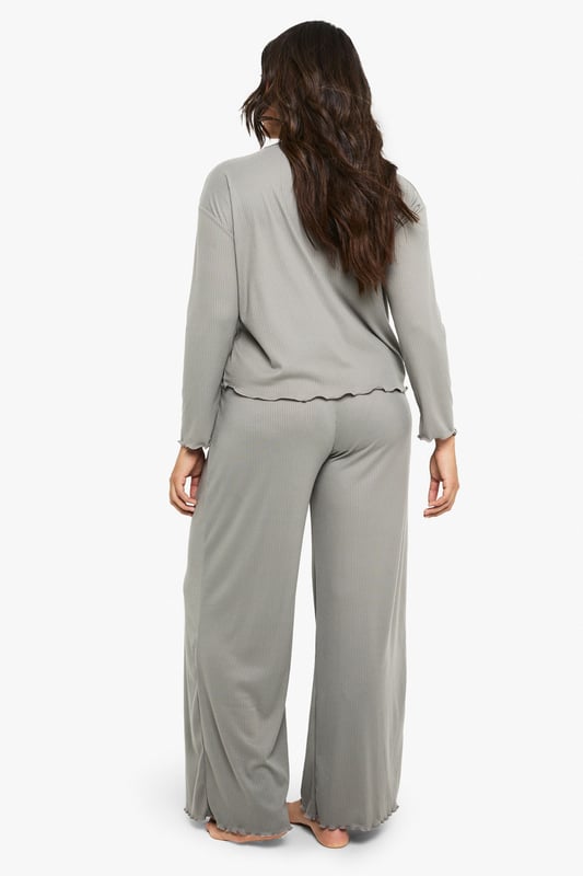 Ribbed texture throughout for added comfort and visual interest
        Relaxed long-sleeve top with distinctive ruffle-trimmed hem
        Wide-leg trousers with matching ruffle detail at the hem
        Soft, stretchy fabric ensures unrestricted movement
        Inclusive plus-size design that flatters your natural silhouette
    
    Embrace laid-back luxury with this Boohoo ribbed loungewear set, thoughtfully designed for those moments when comfort is non-negotiable but style remains essential. The top features a relaxed fit with a playful ruffled hem that adds a feminine touch to casual wear, while the coordinating wide-leg trousers create a balanced silhouette that moves beautifully with you. Perfect for weekend brunches at home, film nights with friends, or simply unwinding after a busy day. Layer with a chunky cardigan and fluffy slippers during colder months, or wear the top with your favourite denim for a quick dash to the shops. This versatile set transitions effortlessly between lounging and casual outings, making it an indispensable addition to your off-duty wardrobe.