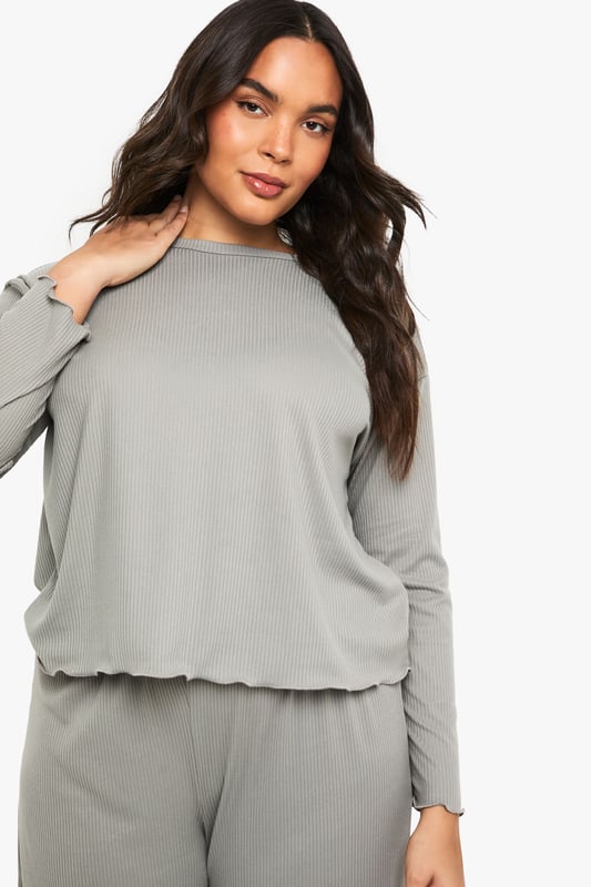Ribbed texture throughout for added comfort and visual interest
        Relaxed long-sleeve top with distinctive ruffle-trimmed hem
        Wide-leg trousers with matching ruffle detail at the hem
        Soft, stretchy fabric ensures unrestricted movement
        Inclusive plus-size design that flatters your natural silhouette
    
    Embrace laid-back luxury with this Boohoo ribbed loungewear set, thoughtfully designed for those moments when comfort is non-negotiable but style remains essential. The top features a relaxed fit with a playful ruffled hem that adds a feminine touch to casual wear, while the coordinating wide-leg trousers create a balanced silhouette that moves beautifully with you. Perfect for weekend brunches at home, film nights with friends, or simply unwinding after a busy day. Layer with a chunky cardigan and fluffy slippers during colder months, or wear the top with your favourite denim for a quick dash to the shops. This versatile set transitions effortlessly between lounging and casual outings, making it an indispensable addition to your off-duty wardrobe.