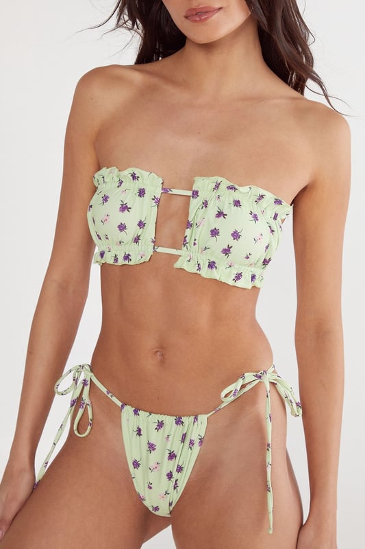 Bandeau bikini top with eye-catching centre cut-out detail and decorative metal bar
        Delicate ruched fabric detailing across the bust for a flattering silhouette
        Tie-side bikini bottoms with adjustable fit for personalised comfort
        Ditsy floral pattern throughout the set for a feminine, playful aesthetic
        Strapless design perfect for minimising tan lines whilst lounging poolside
    
    Make a statement by the water with this striking Nasty Gal bandeau bikini set. The distinctive centre cut-out with metal bar detail creates a contemporary twist on a classic silhouette, whilst the ruched fabric adds texture and dimension. The tie-side bottoms allow for a customised fit that moves with you whether you're taking a refreshing dip or relaxing on a sun lounger. Style with oversized sunglasses and a lightweight kimono for trips to the beach bar, or pair with a flowing maxi skirt for seaside strolls. This versatile set transitions effortlessly from daytime sunbathing to sunset cocktails, making it an essential addition to your holiday wardrobe. Perfect for those who want to combine comfort with head-turning style on their next beachside getaway.