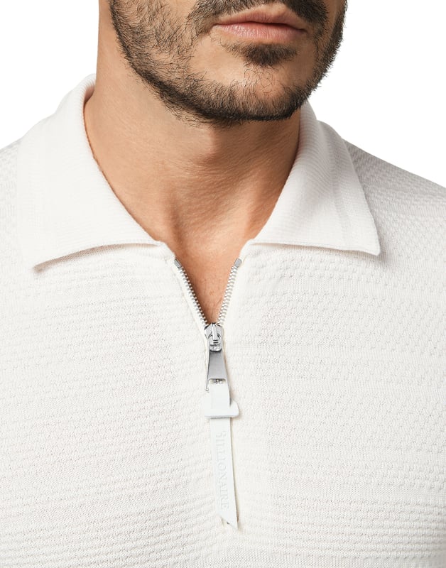 Geweven polo van zuiver merinoswol met lange mouwen. Kraag met rits. Een leren patch met logo is linksonder genaaid. Ribgebreide zomen.