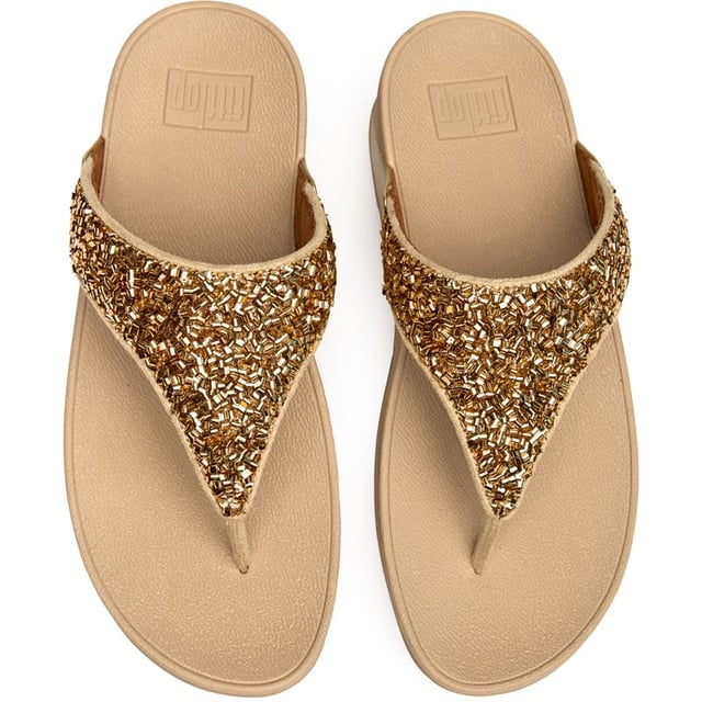 The Fitflop Lulu Shimmerfoil brings glamour to your everyday stride with its eye-catching metallic finish that catches the light beautifully. These sophisticated flip flops feature Fitflop's signature micro wobbleboard sole technology, delivering exceptional comfort and support with every step. The 4cm heel adds a subtle lift while the shimmering synthetic upper creates an effortlessly chic look that transitions seamlessly from poolside to pavement.
