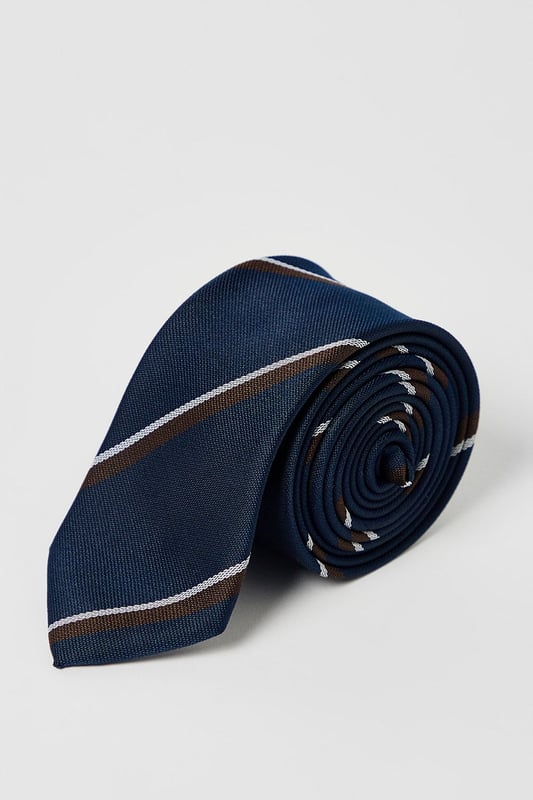 Classic navy tie featuring distinctive heritage diagonal stripes
        Standard width design suitable for both formal and smart-casual occasions
        Crafted with a smooth finish for easy knotting and a polished appearance
        Branded Burton label for authentic style credentials
        Machine washable at 30 degrees for convenient care
    
    This Burton Heritage Stripe Tie offers timeless British style with contemporary versatility. The diagonal stripe pattern presents a refined aesthetic that works brilliantly with a range of shirt options - pair with crisp white for important meetings or light blue for everyday office wear. The tie makes an excellent companion to a navy or grey suit for formal occasions, while also complementing more relaxed ensembles when worn with a blazer and chinos for family gatherings or weekend brunches. Perfect for the gentleman who appreciates classic styling with minimal fuss, this tie transitions seamlessly from daytime professional settings to casual evening drinks with colleagues. A wardrobe essential that reflects considered taste rather than fleeting trends - exactly what the modern British man requires from his accessories.
