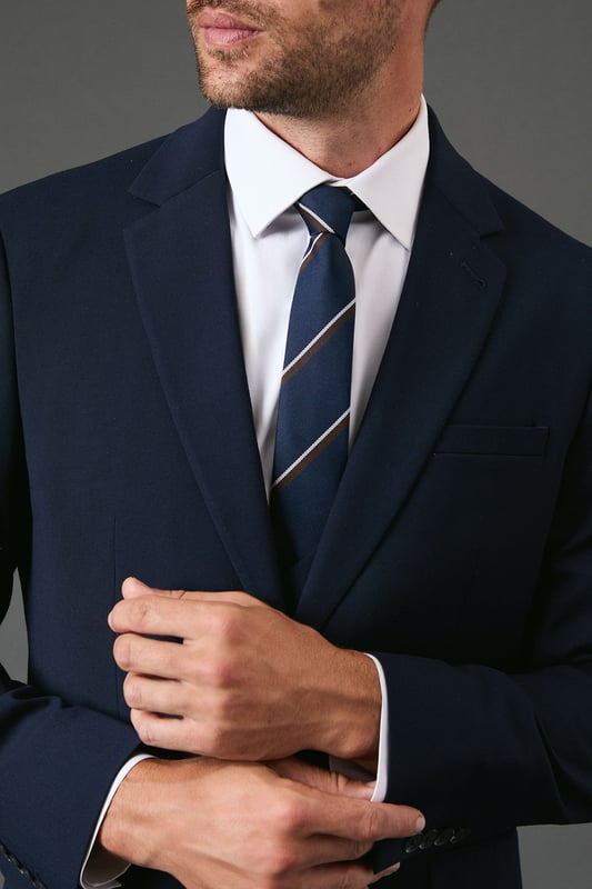Classic navy tie featuring distinctive heritage diagonal stripes
        Standard width design suitable for both formal and smart-casual occasions
        Crafted with a smooth finish for easy knotting and a polished appearance
        Branded Burton label for authentic style credentials
        Machine washable at 30 degrees for convenient care
    
    This Burton Heritage Stripe Tie offers timeless British style with contemporary versatility. The diagonal stripe pattern presents a refined aesthetic that works brilliantly with a range of shirt options - pair with crisp white for important meetings or light blue for everyday office wear. The tie makes an excellent companion to a navy or grey suit for formal occasions, while also complementing more relaxed ensembles when worn with a blazer and chinos for family gatherings or weekend brunches. Perfect for the gentleman who appreciates classic styling with minimal fuss, this tie transitions seamlessly from daytime professional settings to casual evening drinks with colleagues. A wardrobe essential that reflects considered taste rather than fleeting trends - exactly what the modern British man requires from his accessories.