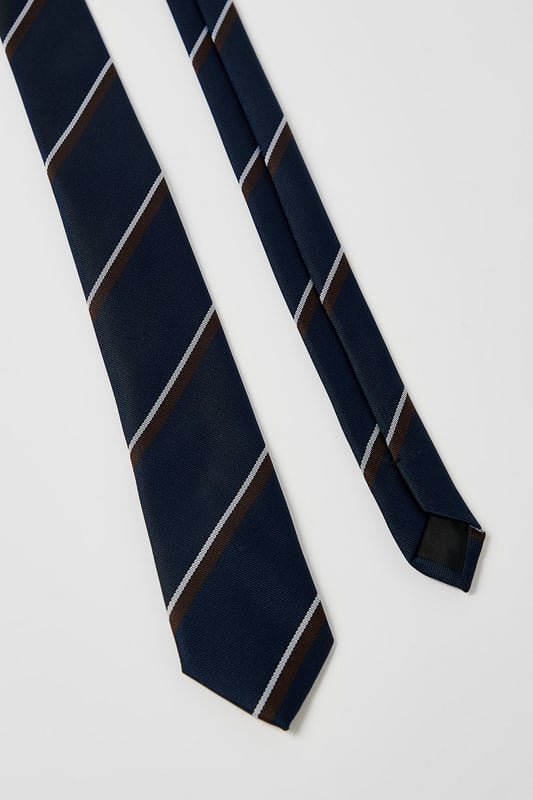 Classic navy tie featuring distinctive heritage diagonal stripes
        Standard width design suitable for both formal and smart-casual occasions
        Crafted with a smooth finish for easy knotting and a polished appearance
        Branded Burton label for authentic style credentials
        Machine washable at 30 degrees for convenient care
    
    This Burton Heritage Stripe Tie offers timeless British style with contemporary versatility. The diagonal stripe pattern presents a refined aesthetic that works brilliantly with a range of shirt options - pair with crisp white for important meetings or light blue for everyday office wear. The tie makes an excellent companion to a navy or grey suit for formal occasions, while also complementing more relaxed ensembles when worn with a blazer and chinos for family gatherings or weekend brunches. Perfect for the gentleman who appreciates classic styling with minimal fuss, this tie transitions seamlessly from daytime professional settings to casual evening drinks with colleagues. A wardrobe essential that reflects considered taste rather than fleeting trends - exactly what the modern British man requires from his accessories.