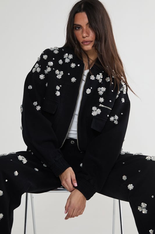 Stunning floral appliqu embellishments
        Oversized, relaxed fit for effortless style
        Front patch pockets for practicality
        Elasticated hem for a snug fit
        Versatile zip-up front closure
    
    Make a bold statement with this eye-catching embellished denim jacket from NastyGal. The scattered floral appliqus create a whimsical, feminine touch that contrasts beautifully with the rugged denim fabric. Perfect for those nights out when you want to turn heads, this jacket can be styled in numerous ways. Pair it with wide-leg jeans and a crop top for a trendy double denim look, or throw it over a slinky dress to add an edgy twist to your evening ensemble. The oversized fit allows for layering, making it ideal for transitional weather. Whether you're heading to a club, meeting friends at a bar, or exploring the urban nightlife, this unique piece will ensure you stand out from the crowd while keeping you comfortably stylish all night long.