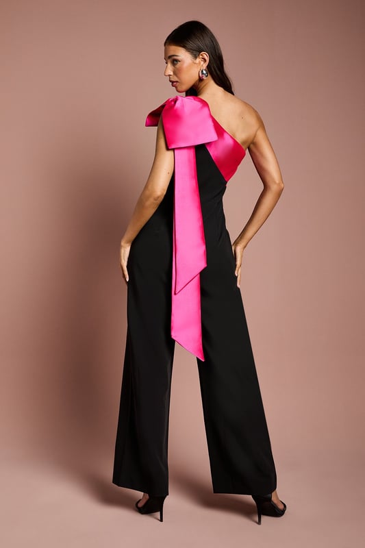 Bow One Shoulder Jumpsuit One-shoulder design with a dramatic bow detail
Wide-leg jumpsuit silhouette with a flattering waist tie
crepe fabric with a luxurious drape
Sleeveless bodice with a fitted waist
Full-length wide legs for an elegant, flowing look
Exuding sophistication and glamour, this jumpsuit is a showstopping choice for formal occasions. The one-shoulder neckline with a striking bow detail adds a touch of drama, while the crepe fabric drapes beautifully for a refined look. Style it with statement jewellery and heels for a wedding or evening event, or pair it with a fascinator and clutch for a day at the races. With its flattering waist tie and flowing wide legs, this jumpsuit is sure to turn heads and make a lasting impression.
