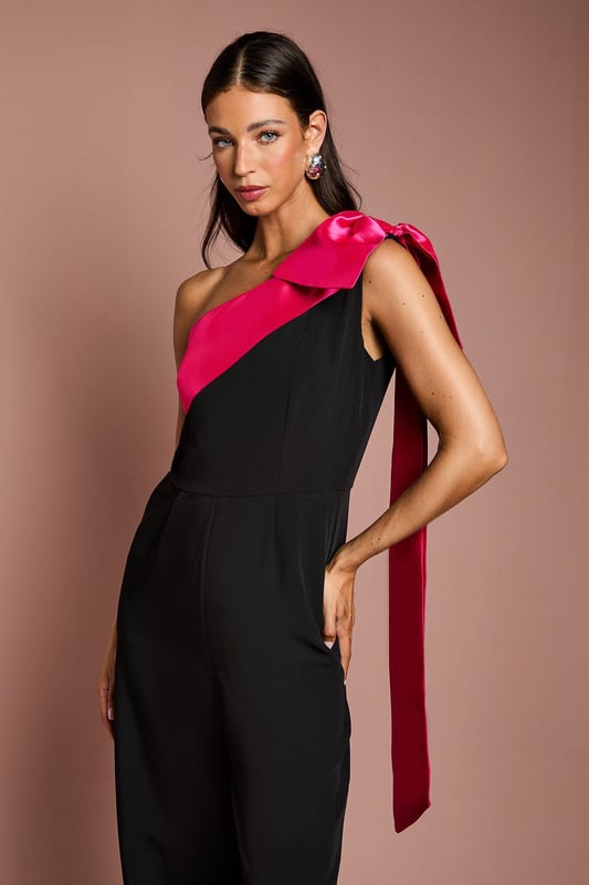 Bow One Shoulder Jumpsuit One-shoulder design with a dramatic bow detail
Wide-leg jumpsuit silhouette with a flattering waist tie
crepe fabric with a luxurious drape
Sleeveless bodice with a fitted waist
Full-length wide legs for an elegant, flowing look
Exuding sophistication and glamour, this jumpsuit is a showstopping choice for formal occasions. The one-shoulder neckline with a striking bow detail adds a touch of drama, while the crepe fabric drapes beautifully for a refined look. Style it with statement jewellery and heels for a wedding or evening event, or pair it with a fascinator and clutch for a day at the races. With its flattering waist tie and flowing wide legs, this jumpsuit is sure to turn heads and make a lasting impression.