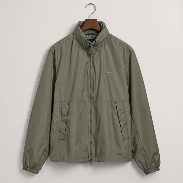 De Light Windshielder is gemaakt van gerecycled polyester met een waterafstotende afwerking en is een lichtgewicht jack met rits voor overgangsweer. De jas heeft een ritssluiting aan de voorkant met zijzakken met ritssluiting, een noodcapuchon in de kraag en een verstelbaar trekkoord in de zoom voor een pasvorm op maat. Het jack heeft een reflecterend GANT-logo op de borst en een geborduurde locker-lus op de capuchon.