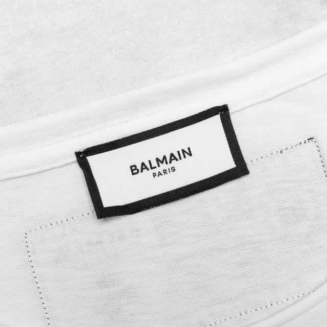 Balmain Sketch Drawing Logo White T-shirt Elevate your wardrobe with the Balmain Sketch Drawing Logo White T-Shirt, a refined piece crafted in Italy from 100% premium cotton for exceptional comfort and durability. Featuring Balmain's distinctive sketch drawing logo, this white t-shirt blends artistic flair with timeless style. Its breathable fabric ensures all-day ease, making it perfect for both casual outings and sophisticated layering. Designed for the modern man who values quality and elegance, this t-shirt offers a versatile addition to any collection, promising a sleek, polished look every time you wear it. Experience luxury and creativity in one essential garment