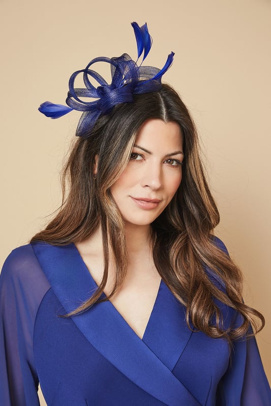 Elegant headband featuring intricate loop detailing and delicate feather embellishments
        Sculptural design creates a striking silhouette perfect for formal occasions
        Lightweight construction ensures comfortable wear throughout the day
        Secure fit with discreet attachment that keeps the headpiece perfectly positioned
        Versatile accessory that complements both updos and flowing hairstyles
    
    Add a touch of sophistication to your occasion ensemble with this exquisite loop and feather headband from Wallis. The artfully arranged loops create a dimensional effect that catches the light beautifully, while the feather accents add movement and drama. As shown, it pairs wonderfully with elegant wrap dresses for a coordinated look that's perfect for weddings, race days and formal garden parties. The headband sits comfortably at an angle, creating a flattering frame for your face without overwhelming your overall appearance. Style with sleek, polished hair for classic refinement, or contrast with loose waves for a more contemporary approach. This statement piece negates the need for elaborate jewellery - simply add delicate earrings to complete your glamorous occasion look.