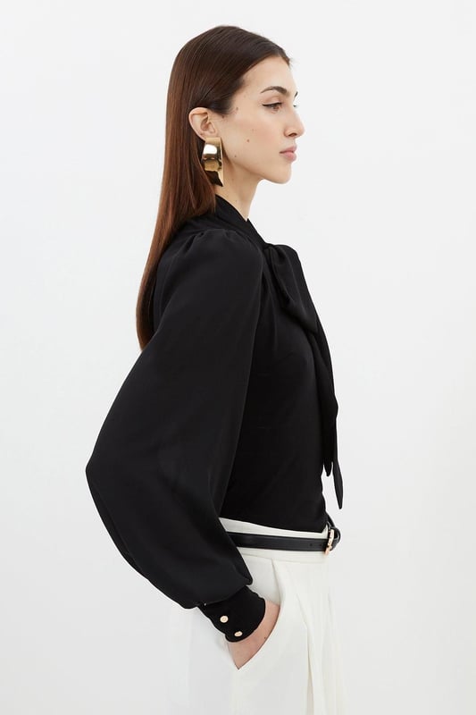 Jersey Ponte And Georgette Mix Tie Neck Long Sleeve Bodysuit This Karen Millen bodysuit combines classic elegance with contemporary styling. The contrasting textures of jersey and georgette create visual interest, while the statement pussy bow adds a touch of feminine charm. The balloon sleeves provide dramatic volume balanced by the fitted bodice, creating a flattering silhouette. Perfect for family gatherings or casual work events, this bodysuit can be dressed down with tailored denim and flats for weekend brunches, or paired with a pencil skirt for more refined occasions. The secure bodysuit design eliminates the need for constant re-tucking, ensuring you maintain a sleek appearance throughout the day. A versatile wardrobe staple that offers both comfort and sophistication. Jersey bodysuit featuring a georgette pussy bow detail Voluminous balloon sleeves with fitted cuffs and button detailing Round neckline Smooth, form-fitting designe
