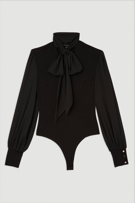 Jersey Ponte And Georgette Mix Tie Neck Long Sleeve Bodysuit This Karen Millen bodysuit combines classic elegance with contemporary styling. The contrasting textures of jersey and georgette create visual interest, while the statement pussy bow adds a touch of feminine charm. The balloon sleeves provide dramatic volume balanced by the fitted bodice, creating a flattering silhouette. Perfect for family gatherings or casual work events, this bodysuit can be dressed down with tailored denim and flats for weekend brunches, or paired with a pencil skirt for more refined occasions. The secure bodysuit design eliminates the need for constant re-tucking, ensuring you maintain a sleek appearance throughout the day. A versatile wardrobe staple that offers both comfort and sophistication. Jersey bodysuit featuring a georgette pussy bow detail Voluminous balloon sleeves with fitted cuffs and button detailing Round neckline Smooth, form-fitting designe