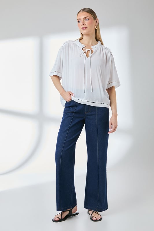 Distinctive ladder trim detailing along the neckline creates visual interest
        Relaxed regular fit with gathered shoulder design for effortless movement
        Elegant tie-front closure adds a feminine touch to this versatile blouse
        Short puff sleeves with trim detail offer a contemporary silhouette
        Textured woven fabric with gentle gathering at the back for added dimension
    
    This charming Principles blouse combines casual comfort with thoughtful design elements. The ladder trim detailing and tie-front feature create a relaxed yet put-together look that transitions seamlessly from day to evening. Style with white trousers and flat sandals as shown for a polished weekend ensemble, or pair with your favourite denim and trainers for casual coffee dates. The lightweight viscose fabric drapes beautifully, making it ideal for warmer days or layering under a cardigan when temperatures drop. Perfect for family gatherings, casual brunches or weekend shopping trips, this blouse offers the versatility to be dressed up with tailored trousers or kept casual with a denim skirt. The subtle textural elements and considered details reflect Principles' commitment to creating wardrobe staples with distinctive character.