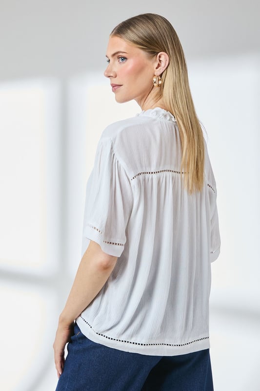 Distinctive ladder trim detailing along the neckline creates visual interest
        Relaxed regular fit with gathered shoulder design for effortless movement
        Elegant tie-front closure adds a feminine touch to this versatile blouse
        Short puff sleeves with trim detail offer a contemporary silhouette
        Textured woven fabric with gentle gathering at the back for added dimension
    
    This charming Principles blouse combines casual comfort with thoughtful design elements. The ladder trim detailing and tie-front feature create a relaxed yet put-together look that transitions seamlessly from day to evening. Style with white trousers and flat sandals as shown for a polished weekend ensemble, or pair with your favourite denim and trainers for casual coffee dates. The lightweight viscose fabric drapes beautifully, making it ideal for warmer days or layering under a cardigan when temperatures drop. Perfect for family gatherings, casual brunches or weekend shopping trips, this blouse offers the versatility to be dressed up with tailored trousers or kept casual with a denim skirt. The subtle textural elements and considered details reflect Principles' commitment to creating wardrobe staples with distinctive character.