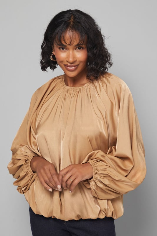 Gathered Puff Hem Blouse Elegant gathered neckline creating a soft, flattering drape
Voluminous balloon sleeves with gathered cuffs for dramatic effect
Relaxed, flowing silhouette that offers comfortable movement
Distinctive puff hem design that creates a subtle blouson effect
Versatile length perfect for tucking or wearing loose over trousers
This sophisticated Wallis blouse combines comfort with effortless style through its distinctive gathered details and flowing silhouette. The statement balloon sleeves create a dramatic yet wearable look, while the gathered neckline offers a flattering frame for delicate jewellery. Style with dark denim jeans and ankle boots for casual family gatherings, or pair with tailored wide-leg trousers and ballet flats for lunch with friends. The puff hem design adds interest to this versatile piece, allowing it to be worn loose for a relaxed feel or partially tucked for a more defined waistline. Perfect for those who appreciate comfortable glamour in their daywear, this blouse transitions seamlessly from weekend brunches to casual office settings. Add gold-toned hoop earrings and a simple crossbody bag to complete this sophisticated yet effortless ensemble.