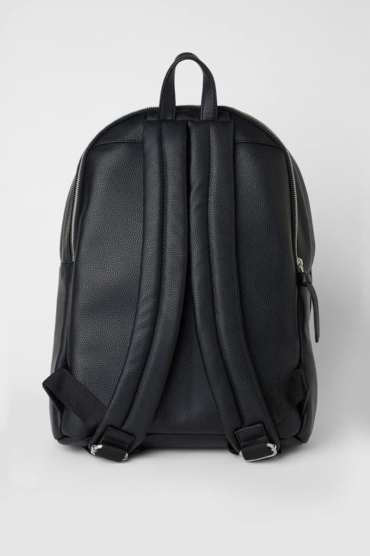 Black Grain Faux Leather Commuter Backpack Textured grain faux leather finish for a sophisticated appearance
Front zip pocket for easy access to essentials
Spacious main compartment ideal for daily commuting needs
Padded adjustable shoulder straps for comfortable carrying
Classic silhouette with clean lines for versatile styling
This commuter backpack combines practicality with understated style, perfect for the modern man on the move. The sleek design transitions effortlessly from morning commutes to weekend adventures, with ample space for your laptop, documents and daily essentials. Pair with tailored trousers and a crisp shirt for office days, or team with dark denim jeans and a casual jacket for pub meet-ups with mates. The durable construction makes it an ideal companion for sporting events or weekend trips away. The minimalist aesthetic ensures this backpack will complement your existing wardrobe without overwhelming your look. A practical yet stylish solution for the man who values both function and classic design in his everyday accessories.