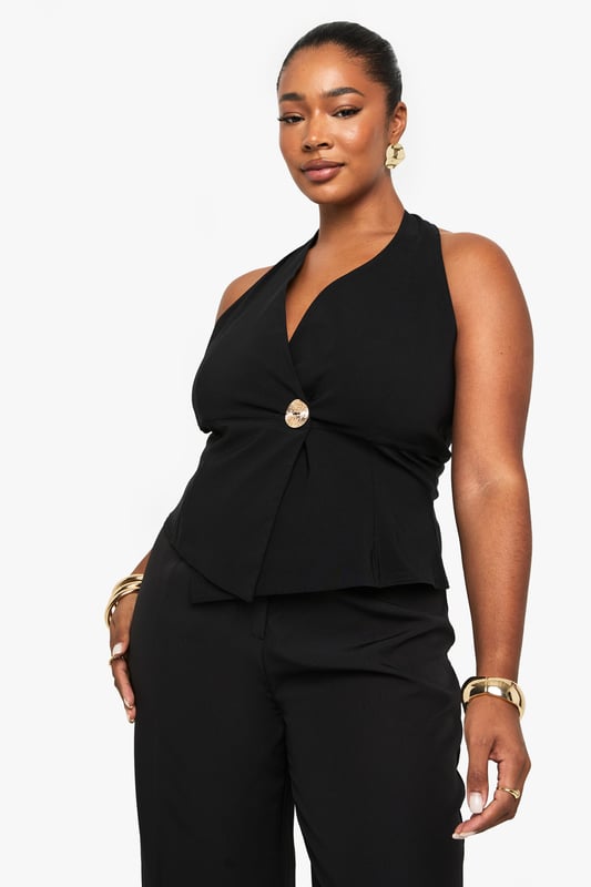 Striking halterneck design with elegant wrap front detail
        Sophisticated gold-tone button accent at the waist
        Sleeveless silhouette with open back for a daring look
        Flattering wrap style that accentuates your curves
        Versatile piece that can be dressed up or down for various occasions
    
    Make a statement on your next night out with this chic halterneck wrap waistcoat. The sophisticated design features a flattering wrap front secured with a standout gold-tone button that adds just the right amount of glamour. Perfect for the confident Boohoo woman who loves to showcase her style, this piece pairs beautifully with wide-leg trousers as shown for a coordinated ensemble that commands attention. Style with statement jewellery and strappy heels for drinks with the girls, or layer over a fitted bodysuit with jeans for a more casual take on nightlife dressing. The open back design offers a sultry touch that's ideal for warm evenings in the city. This versatile top transitions effortlessly from early evening cocktails to late-night dancing, ensuring you remain the centre of attention wherever the night takes you.