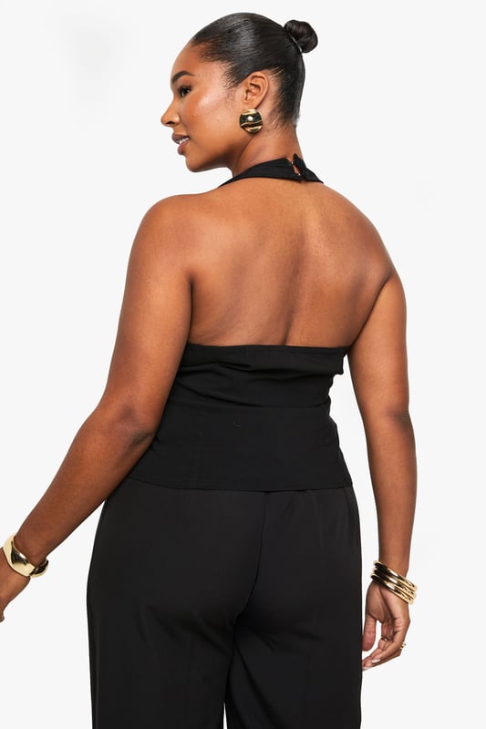 Striking halterneck design with elegant wrap front detail
        Sophisticated gold-tone button accent at the waist
        Sleeveless silhouette with open back for a daring look
        Flattering wrap style that accentuates your curves
        Versatile piece that can be dressed up or down for various occasions
    
    Make a statement on your next night out with this chic halterneck wrap waistcoat. The sophisticated design features a flattering wrap front secured with a standout gold-tone button that adds just the right amount of glamour. Perfect for the confident Boohoo woman who loves to showcase her style, this piece pairs beautifully with wide-leg trousers as shown for a coordinated ensemble that commands attention. Style with statement jewellery and strappy heels for drinks with the girls, or layer over a fitted bodysuit with jeans for a more casual take on nightlife dressing. The open back design offers a sultry touch that's ideal for warm evenings in the city. This versatile top transitions effortlessly from early evening cocktails to late-night dancing, ensuring you remain the centre of attention wherever the night takes you.
