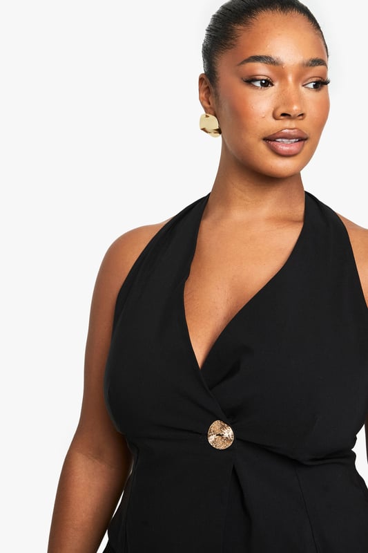 Striking halterneck design with elegant wrap front detail
        Sophisticated gold-tone button accent at the waist
        Sleeveless silhouette with open back for a daring look
        Flattering wrap style that accentuates your curves
        Versatile piece that can be dressed up or down for various occasions
    
    Make a statement on your next night out with this chic halterneck wrap waistcoat. The sophisticated design features a flattering wrap front secured with a standout gold-tone button that adds just the right amount of glamour. Perfect for the confident Boohoo woman who loves to showcase her style, this piece pairs beautifully with wide-leg trousers as shown for a coordinated ensemble that commands attention. Style with statement jewellery and strappy heels for drinks with the girls, or layer over a fitted bodysuit with jeans for a more casual take on nightlife dressing. The open back design offers a sultry touch that's ideal for warm evenings in the city. This versatile top transitions effortlessly from early evening cocktails to late-night dancing, ensuring you remain the centre of attention wherever the night takes you.