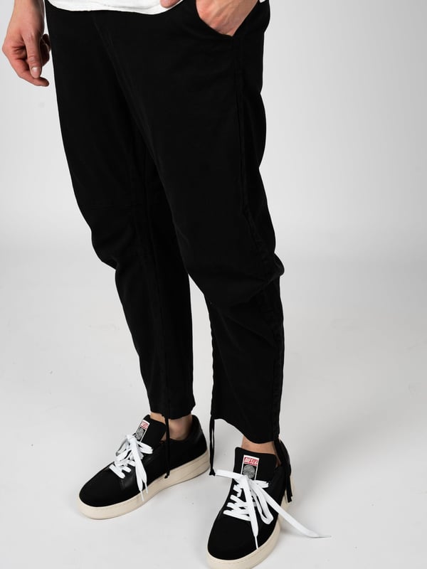 El diseño sencillo de estos pantalones es la elección perfecta para los amantes de lo clásico, que valoran el minimalismo y la elegancia en la vestimenta diaria, mientras desean mantener la libertad de movimiento y la comodidad al llevarlos.

Con cierre de cremallera, estos pantalones no solo ofrecen comodidad, sino también una puesta rápida y fácil, lo que es especialmente útil en un estilo de vida ajetreado donde cada segundo cuenta.

Con una banda elástica cosida en la cintura, estos pantalones se adaptan a la figura, asegurando así comodidad y estilo, lo que los hace una excelente opción para diversas ocasiones, desde reuniones sociales hasta salidas casuales.

Con dos bolsillos en el frente y detrás, estos pantalones ofrecen practicidad y funcionalidad, permitiendo guardar objetos pequeños como llaves o teléfono, siempre al alcance de la mano.

Los detalles de costura en las rodillas añaden un carácter único y una apariencia moderna, destacando al mismo tiempo la atención al detalle y la alta calidad de fabricación, lo que es un distintivo de este producto.

La posibilidad de ajustar el largo de las piernas con cordones permite adaptar los pantalones a preferencias individuales, asegurando no solo comodidad, sino también un aspecto moderno, independientemente de la situación o del estilo.

Fabricados con tela de alta calidad, estos pantalones no solo son duraderos y resistentes al uso diario, sino también agradables al tacto, lo que se traduce en comodidad al usarlos durante todo el día.

Producidos en Italia, estos pantalones reflejan las mejores tradiciones del artesanado italiano, combinando elegancia, precisión en la fabricación y un estilo único que capta la atención y destaca la individualidad del portador.