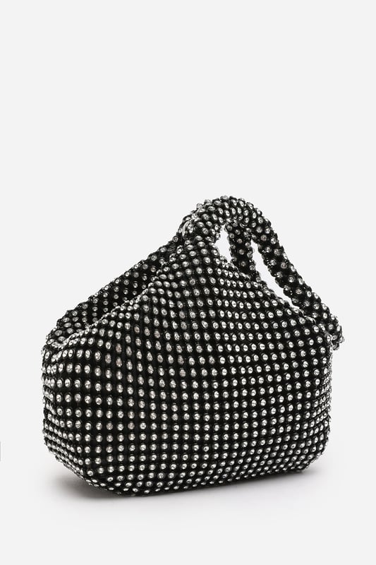 Add sparkle to your night with this Cascabel mini chainmail pouch bag, designed to dazzle at parties, weddings, or festive occasions. Its compact silhouette features shimmering crystal-style embellishments and a stylish knotted wristlet strap for easy carrying. Lightweight yet eye-catching, it's the perfect accessory for carrying your small essentials in glamorous style. A chic statement piece that blends retro charm with modern flair. Key Features: • Material: Rhinestone-embellished chainmail mesh • Dimensions: 16cm (L) x 14cm (H) x 10cm (W) • Fastening: Hidden zip closure at the top • Detail: Knotted wristlet strap for a secure and stylish hold